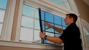 Technician fitting a custom heavy duty solar window screen frame to a Dallas window casing