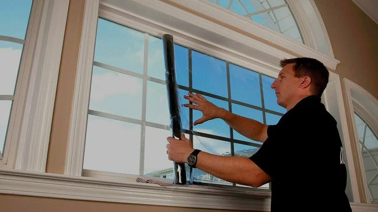 Technician fitting a custom heavy duty solar window screen frame to a Dallas window casing